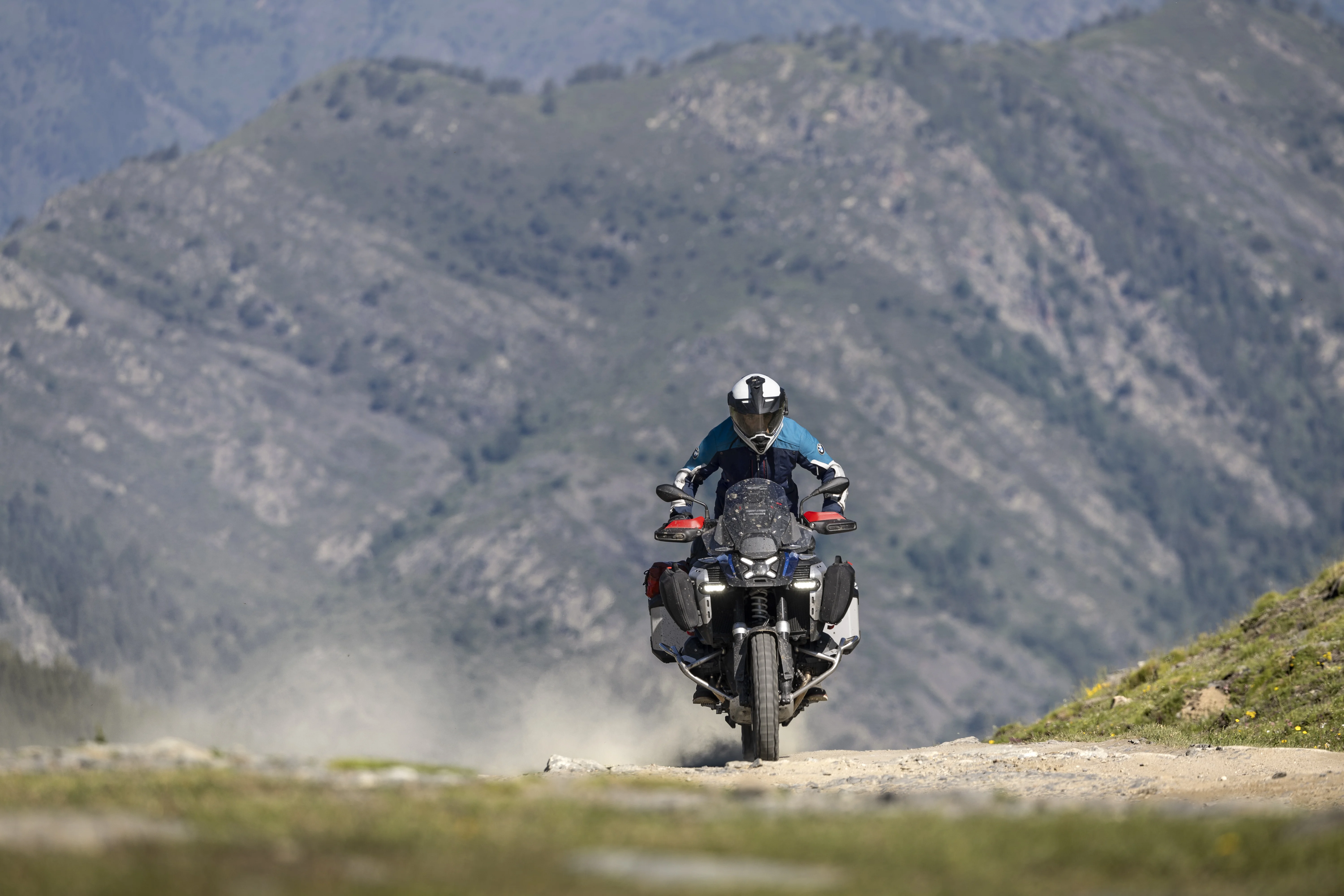 2026 BMW R 1300 GS Adventure on a mountain road with rugged terrain in the background